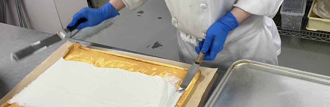 製造現場でチーズケーキを仕上げるスタッフ